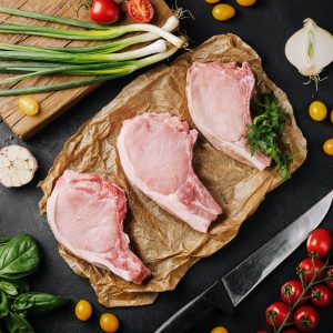 Several raw pork steaks on baking paper